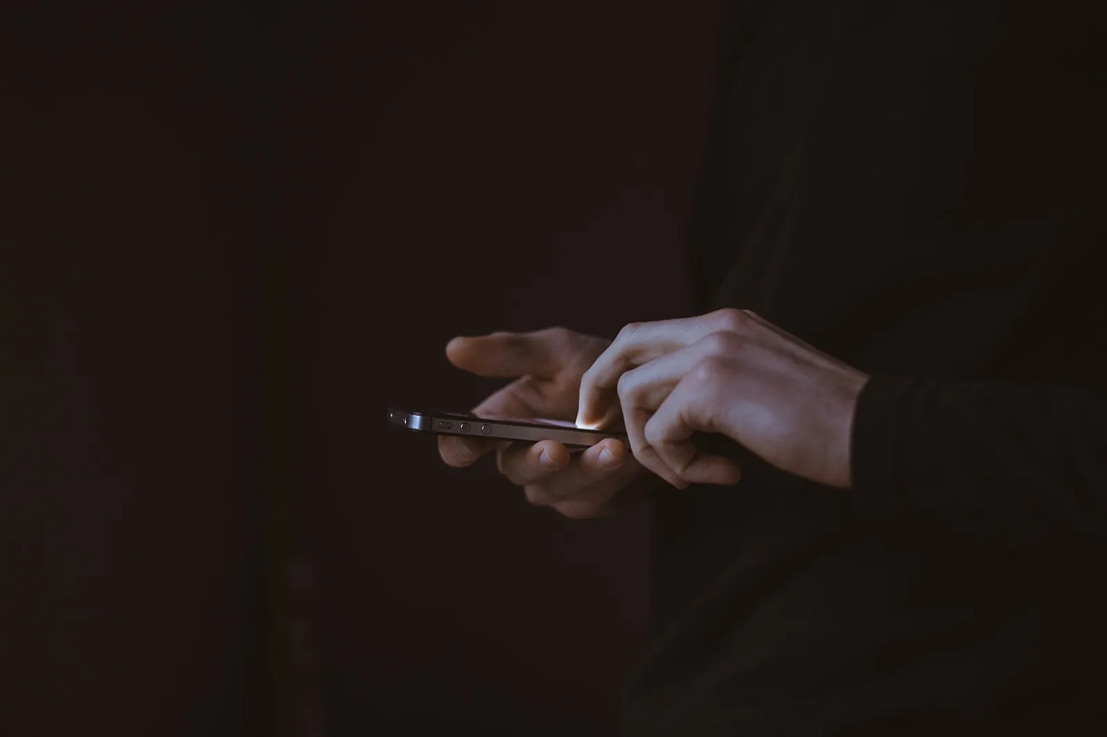 Hands holding a smartphone in a dim room